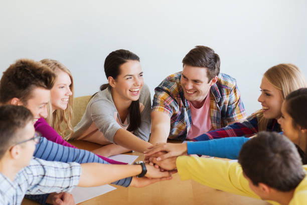 istock group of smiling students with hand on top 1321464324