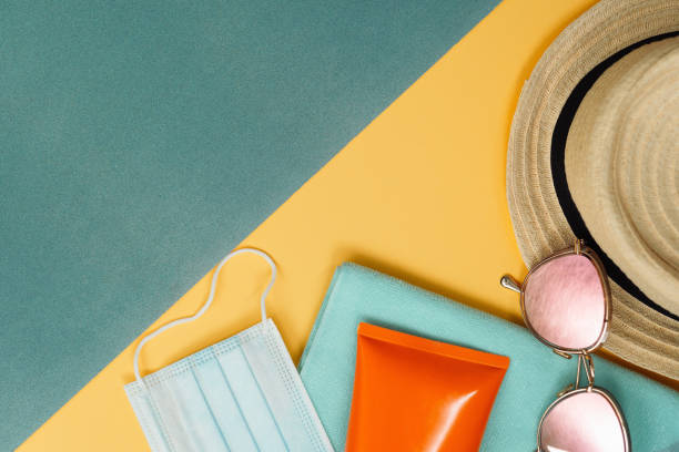 Beach composition with straw hat, covid mask and sunglasses