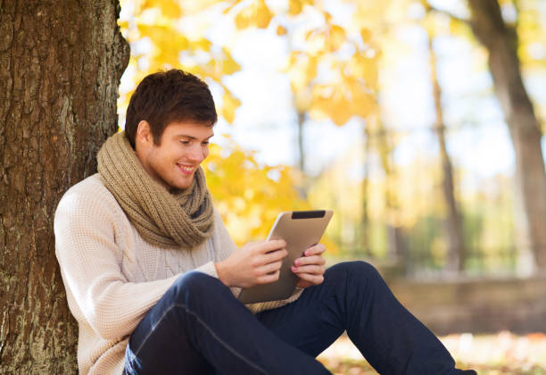 istock smiling young man with tablet pc in autumn park 1321466030