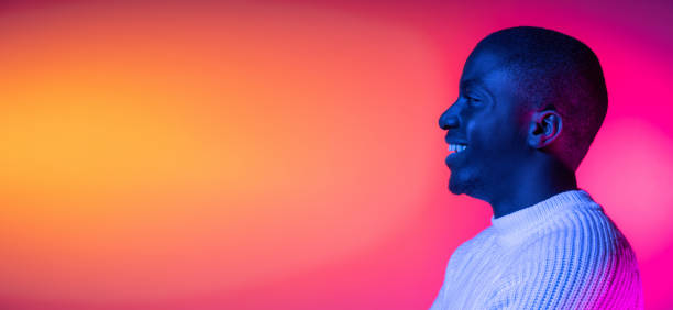istock Side view. One young happy African handsome man isolated over gradient pink yellow neon background. 1321470543