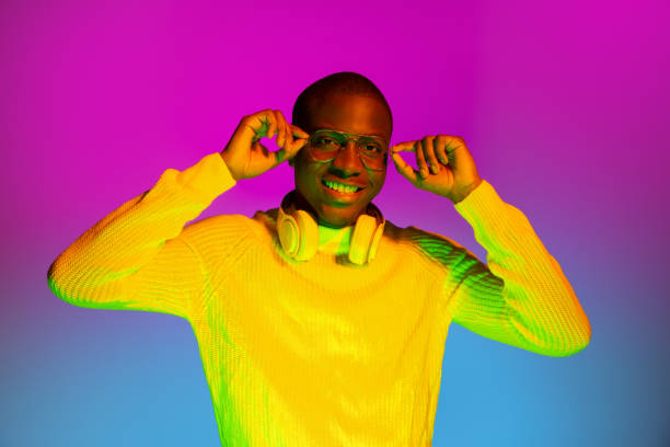 istock Smiling happy African handsome man posing isolated over gradient magenta yellow neon background. 1321470594