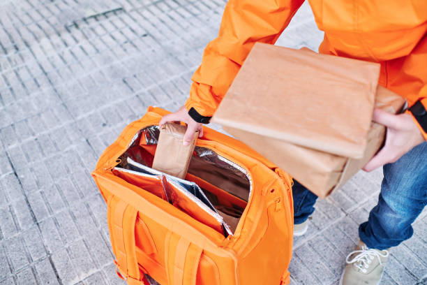 istock delivery man picking up packages from the delivery backpack on the sidewalk 1321475202
