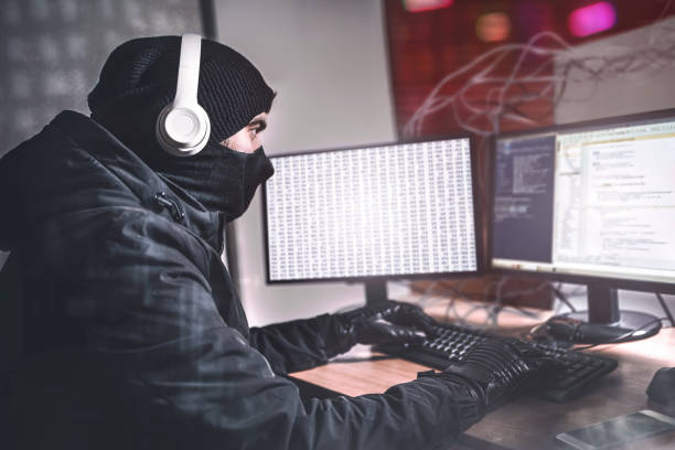 istock Teenage Hacker man Using her Computer to Organize Malware Attack on Global Scale. She's in Underground Secret Location Surrounded by Displays and Cables. 1321475360