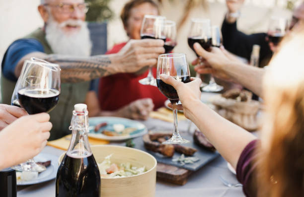 istock Multi generational people cheering with wine and eating outdoors at home - Focus on center hand holding glass 1321475589
