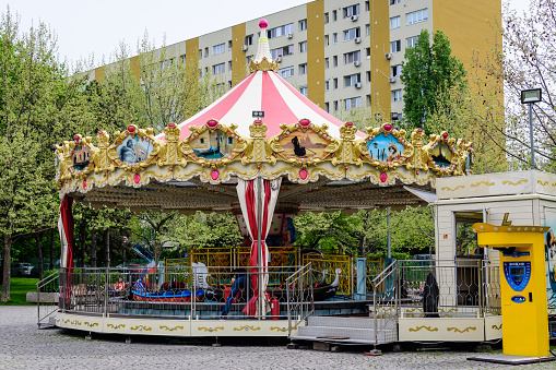 Bucharest, Romania - 1 May 2021: Colorful children colorful carousel with mixed plastic and metallic toys and materials in Alexandru Ioan Cuza (IOR) Park in a cloudy spring day with white sky