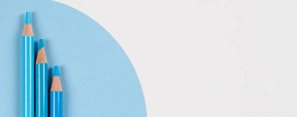 istock Light blue colored pencils on geometric blue and white background. Monochrome colors. Top view 1321478060