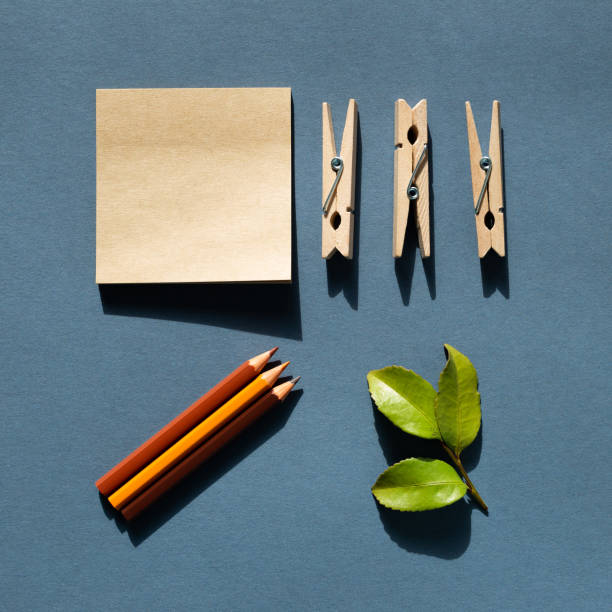 istock Notepad and colored pencils and wooden clips and green leaf on desk. navy blue background. Work and study place. flat lay, top view, copy space 1321479316