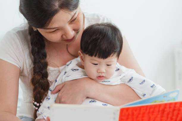 Young happy Asian woman reading book with the little baby boy. Development education concept Young happy Asian woman reading book with the little baby boy. Development education concept. korean baby stock pictures, royalty-free photos & images