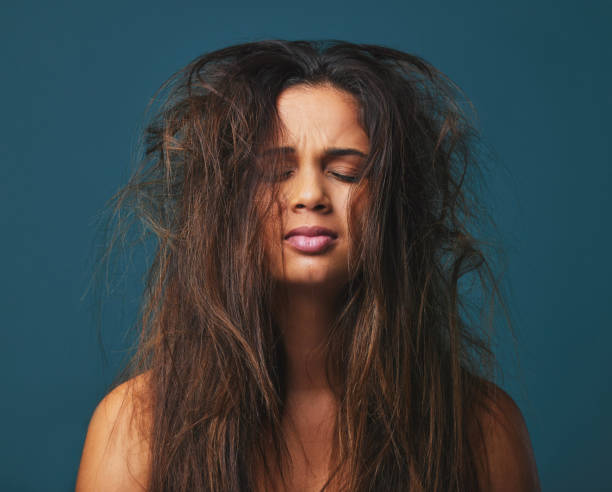 scatto in studio di una bella giovane donna con i capelli disordinati in posa su uno sfondo blu - untidy hair foto e immagini stock