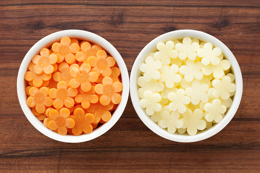 Two bowls containing flower shaped sliced carrots and potatoes