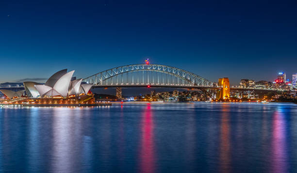 panorama-nachtansicht von sydney harbour und cbd gebäuden am ufer in nsw australien - sydney harbor sydney australia australia sydney harbor bridge stock-fotos und bilder