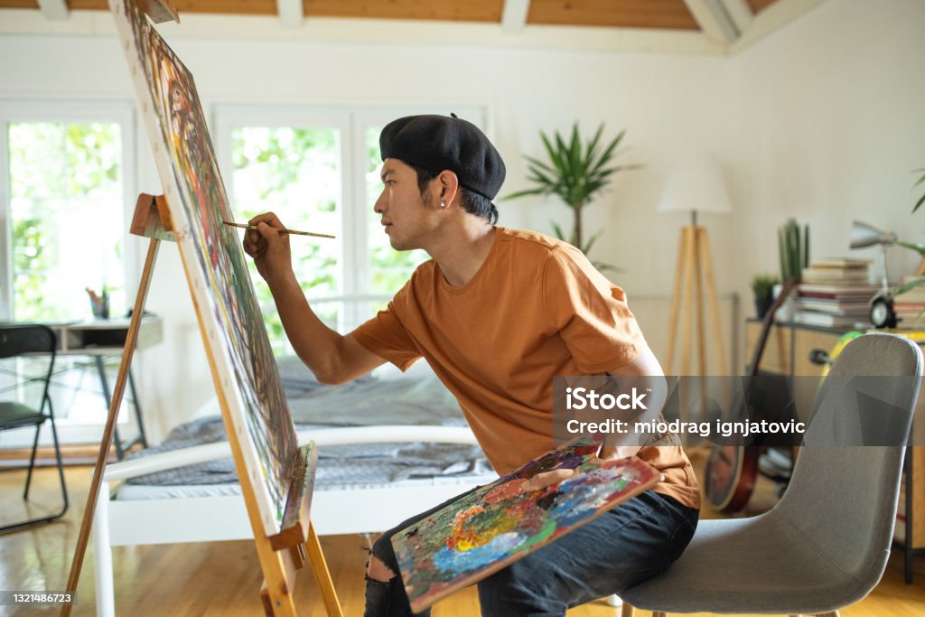 Japanese man spending weekend morning painting in his bedroom at home Painting - Activity Stock Photo