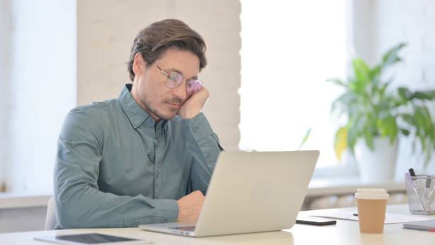 istock Middle Aged Man with Laptop taking Nap in Office 1321490944