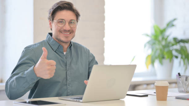 istock Thumbs Up by Middle Aged Man with Laptop in Office 1321490979