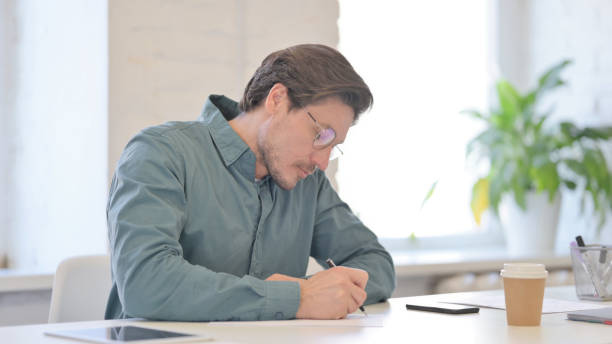 istock Pensive Middle Aged Man Writing on Paper, Thinking 1321491117