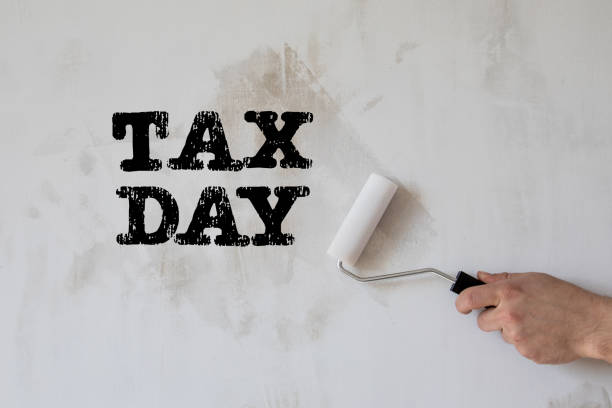 istock Tax Day. Paint roller in a man's hand. Concrete wall background 1321492004