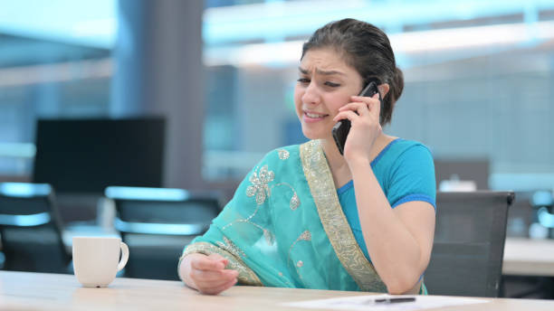 istock Young Indian Woman Angry on Smartphone at Work 1321494047