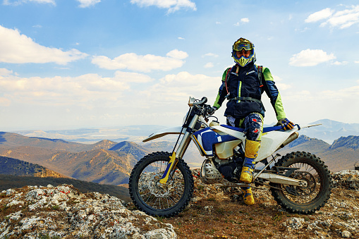 Man in sport equipment riding a motorcross sport bike in mountains
