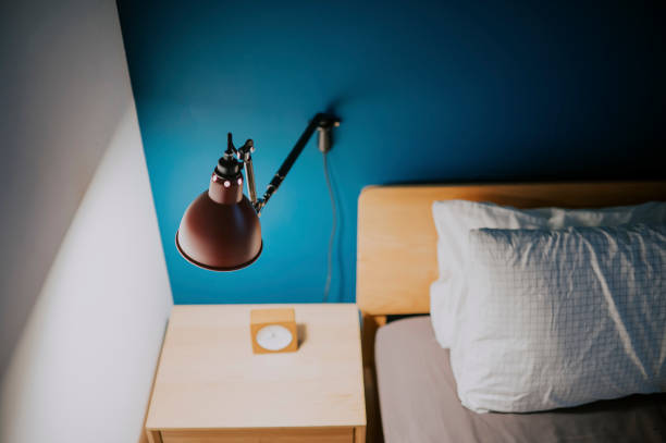 istock bedroom at night illuminated by electric lamp with clock on night table beside the bed with blue wall 1321502103