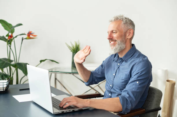 istock Cheerful mature grey-haired man using laptop for video call 1321505482