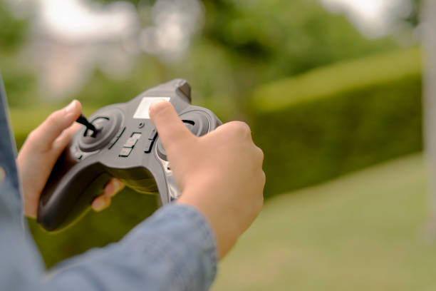 gros plan des mains d’un enfant jouant avec la télécommande de son drone jouet. concept de contrôle par drone. espace de copie - video game joystick leisure games control photos et images de collection