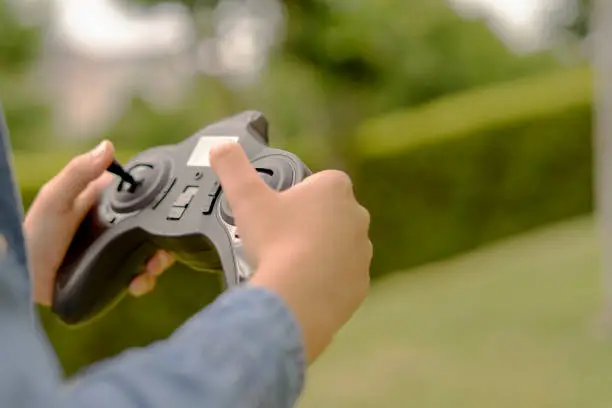 Photo of Close up of a child's hands playing with the remote control of his toy drone. Concept of drone control. Copy space