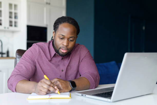 istock Intelligent and smart African-American male entrepreneur using laptop computer and takes notes 1321507685