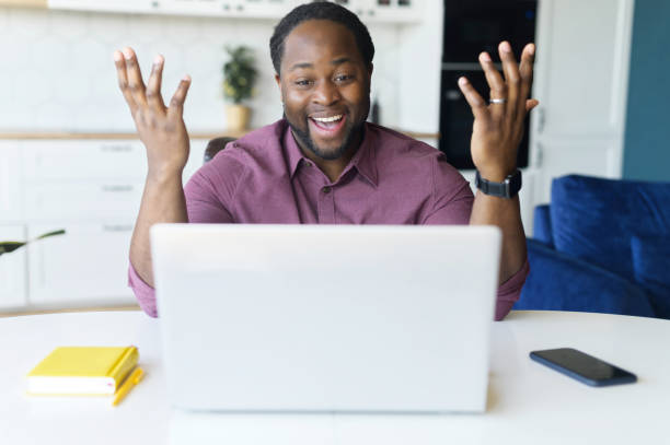 istock Surprised happy African-American male freelancer using laptop for remote work from home 1321508400