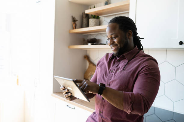 istock Joyful and positive African-American guy scrolling on touchscreen of digital tablet 1321509675