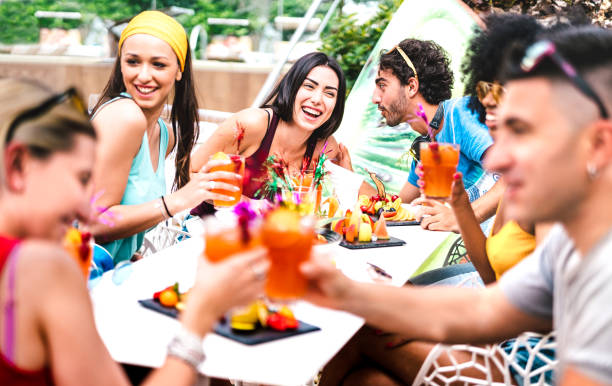 glückliche freunde trinken cocktails auf pool-party - junge leute mit spaß in luxus-resort-restaurant - urlaub lifestyle-konzept mit jungs und mädchen genießen getränke und obst - fokus auf zentrale frau - drink swimming pool cocktail poolside stock-fotos und bilder