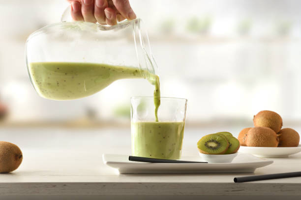 istock Person serving kiwi drink from jug on kitchen bench 1321518457