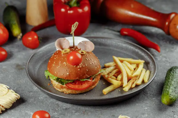 Photo of Children's burger in the form of a mouse. Burger from the children's menu with fries and sauce