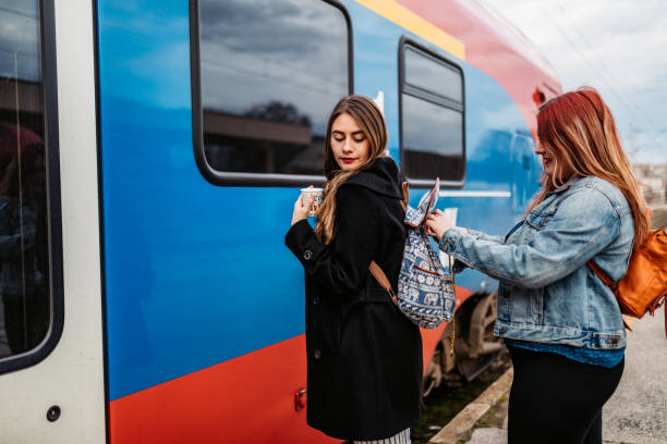 Woman helping friend with backpack on train station while they waiting for train.