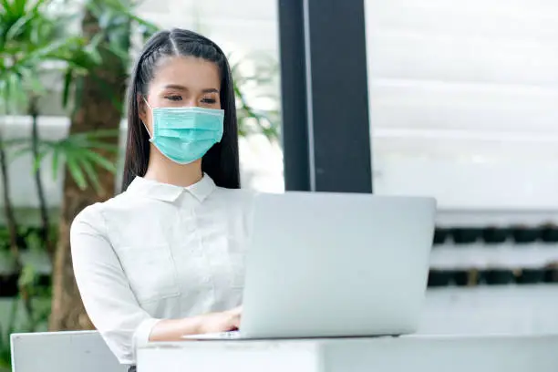 Photo of Asian woman with hygiene mask sit in home garden and use laptop during work at home