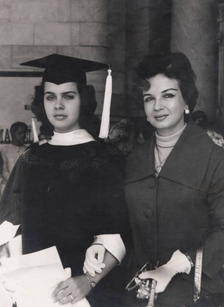 imagen vintage de los años 50 de una adolescente posando con su madre el día de su graduación - poses para fotos de graduación fotografías e imágenes de stock