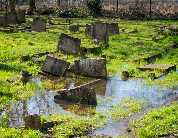 On a sunny day in winter, part of a cemetery is flooded and some of the graves are submerged. These graves are quite old and the soil level has changed since they were created. (Names removed from gravestones.)