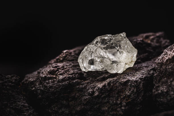 istock rough diamond on isolated black background, rare and precious mineral concept. 1321535483