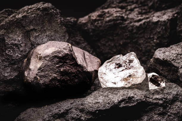 istock rough diamond next to a cut diamond, and coal stone in a coal mine. 1321535517