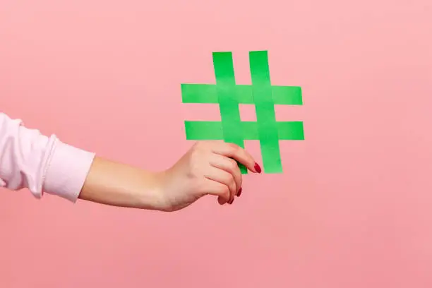 Photo of Closeup of yellow hash sign, female hand holding paper hashtag, symbol of social network trends and popular comments, famous blog content, promotion