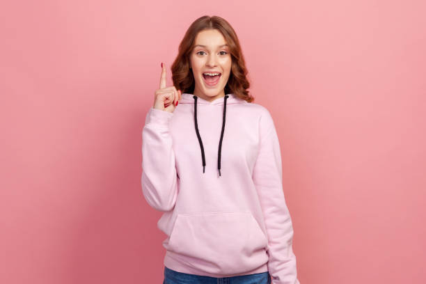 portrait of excited inspired teen with brown hair pointing finger up looking at camera with toothy smile, happy with new great idea, find solution - finger raised imagens e fotografias de stock
