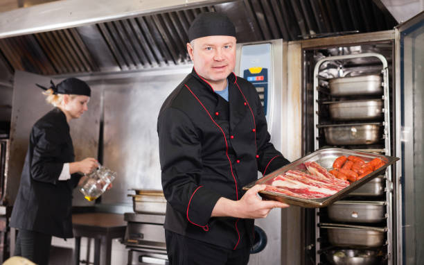 istock Chef holding baking tray with raw meat products 1321542582