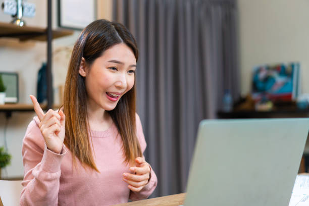 istock Asian woman using laptop making video call while working at home 1321543566