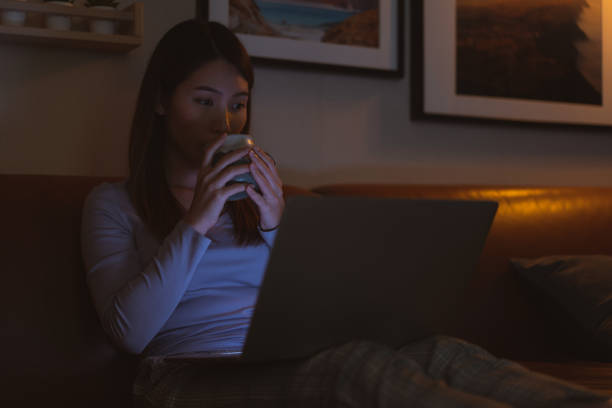 istock Asian woman drinking hot milk while watching a movie at night 1321543596