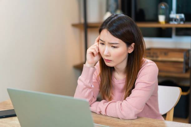 istock Concentrated Asian woman making decision while working on laptop at home 1321543646