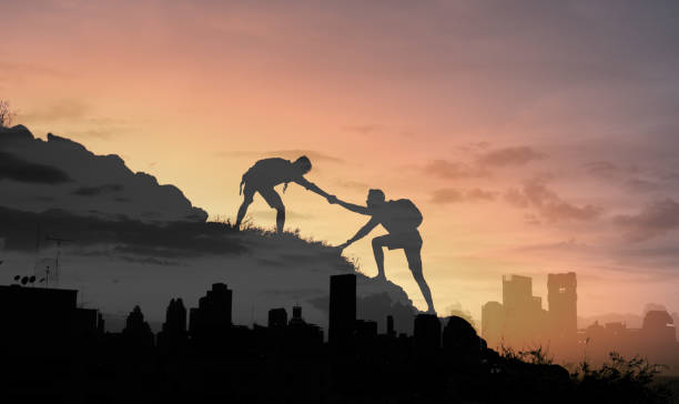 istock People helping each other up a mountain overlooking a city. 1321550257