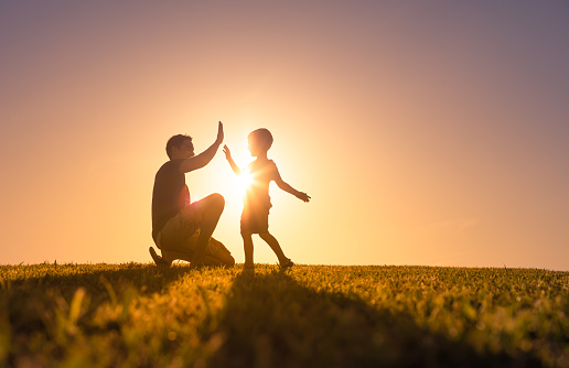 Father playing with his son outdoors at sunset.