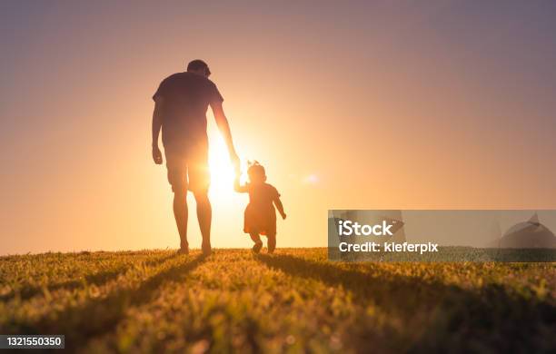 Father And Daughter Holding Hands And Walking At Sunset Outdoors Stock Photo - Download Image Now