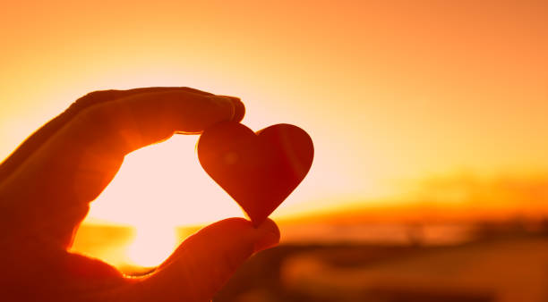 istock Hand holding heart against beautiful sunset. 1321550685