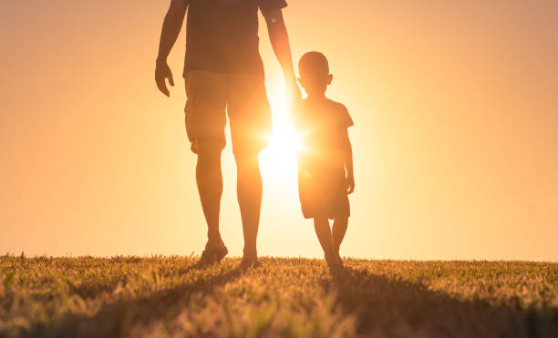 istock Man walking with his son at sunset.  Father son bonding. 1321550705