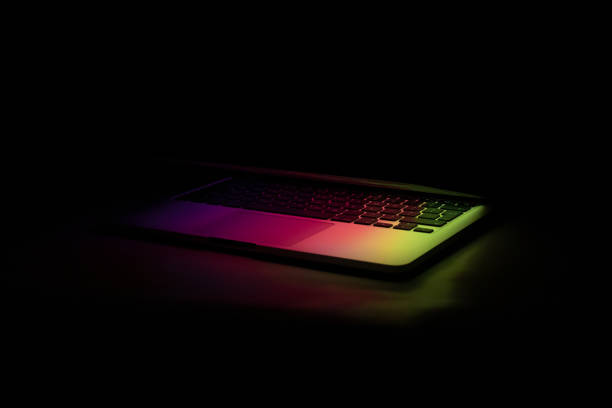 istock a laptop half closed in the dark with colourful glow 1321551347